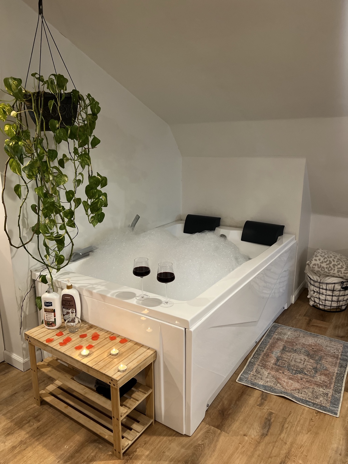 Bubble-filled jetted tub with wine, tea lights and rose petals under the eaves