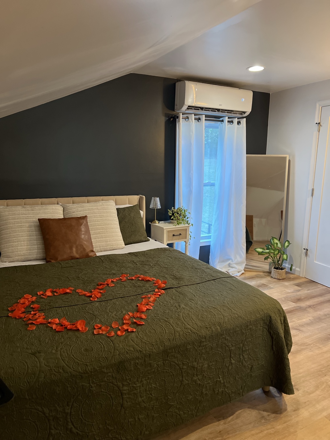 King bed dressed in olive with rose petals arranged in a heart