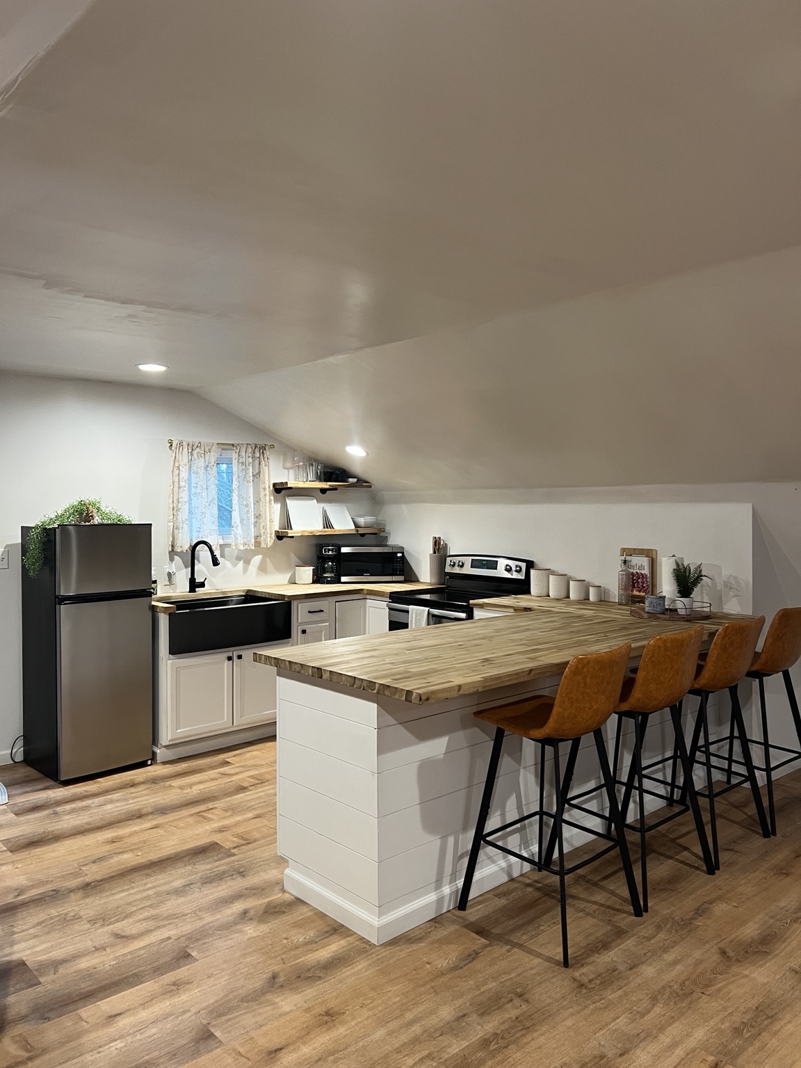 Full kitchen with butcher-block breakfast bar and four leather stools