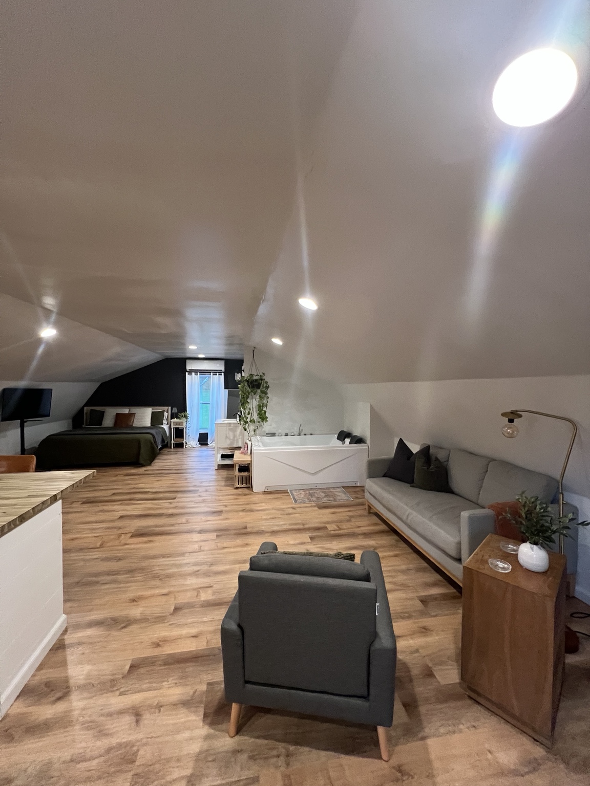 Lounge area with sofa, armchair and the tub and bed beyond