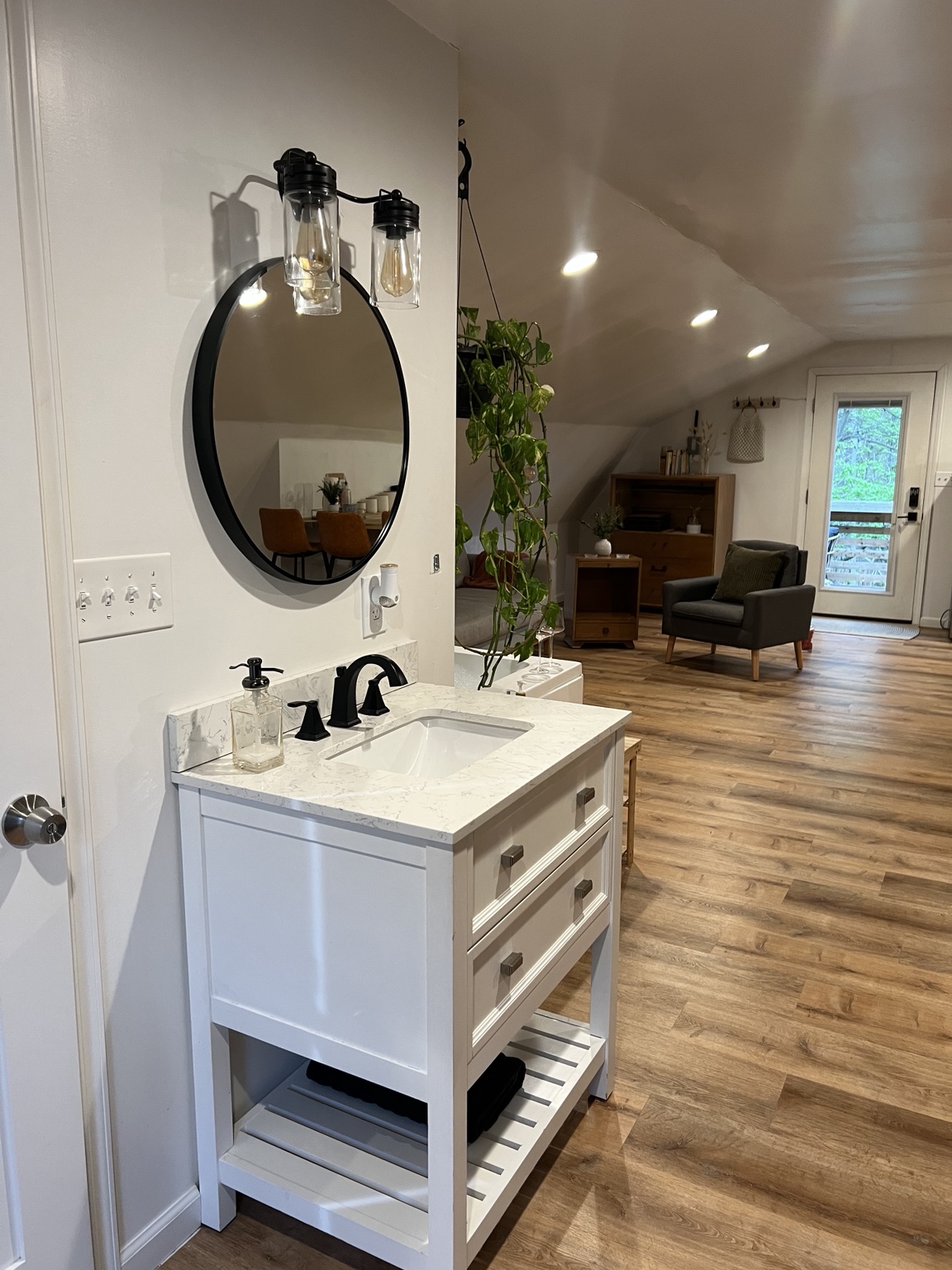 Vanity with round mirror and view down the loft toward the deck door