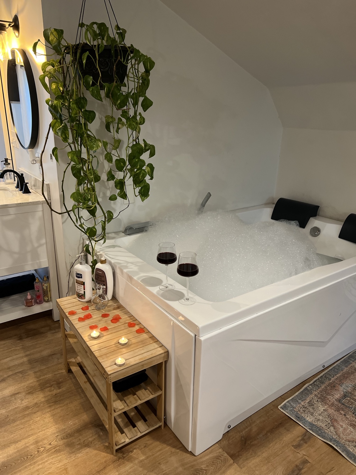 The soaking tub beside the vanity with rose petals and tea lights