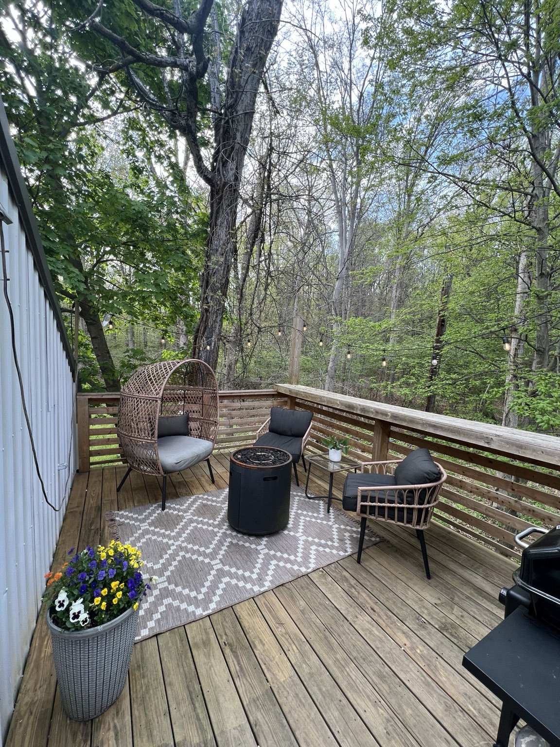 Private deck with egg chair, fire table and string lights in the trees