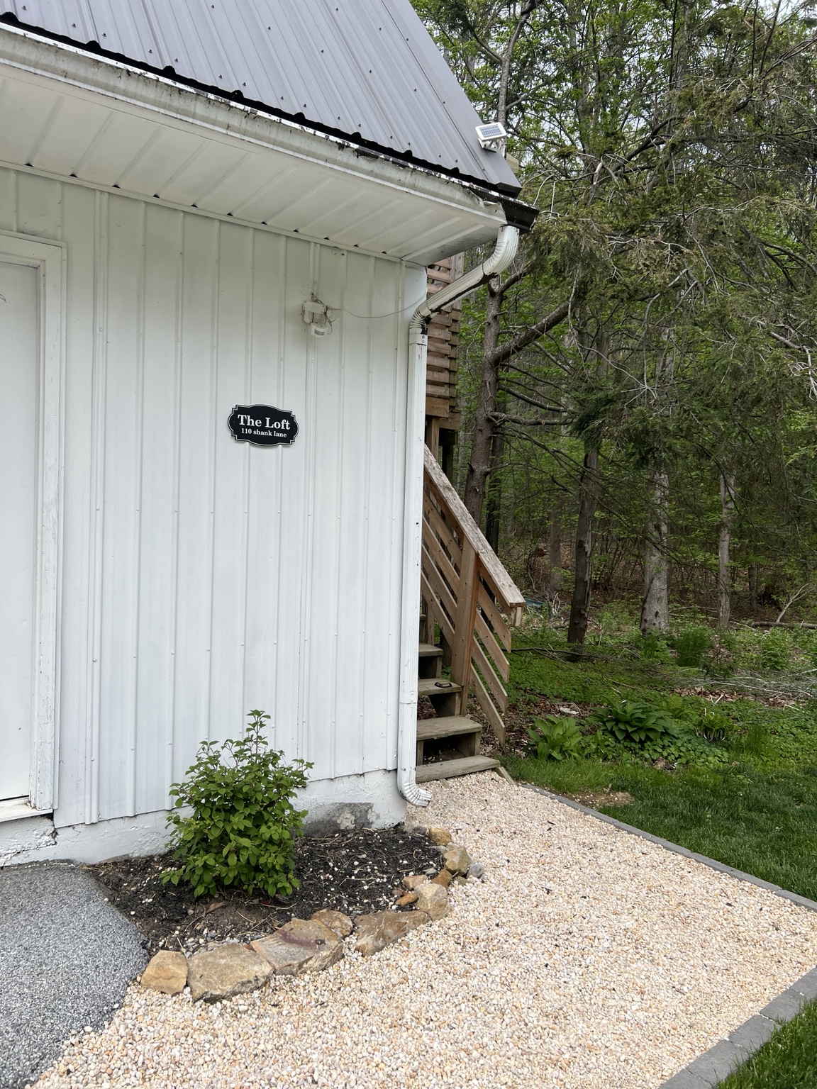 The Loft sign on the white barn beside the woods