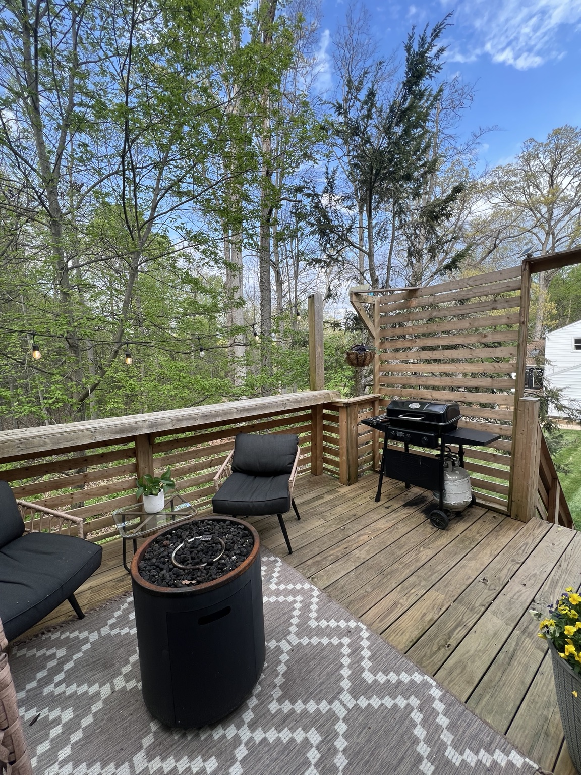 Fire table, rattan seating and grill behind the deck's privacy screen