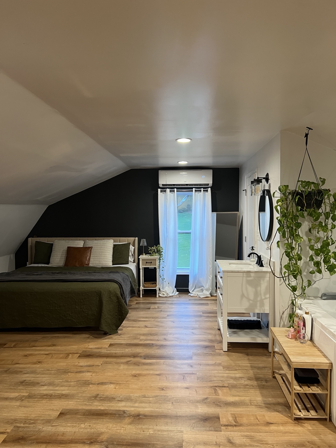 King bed against the black feature wall with the tub nook down the loft