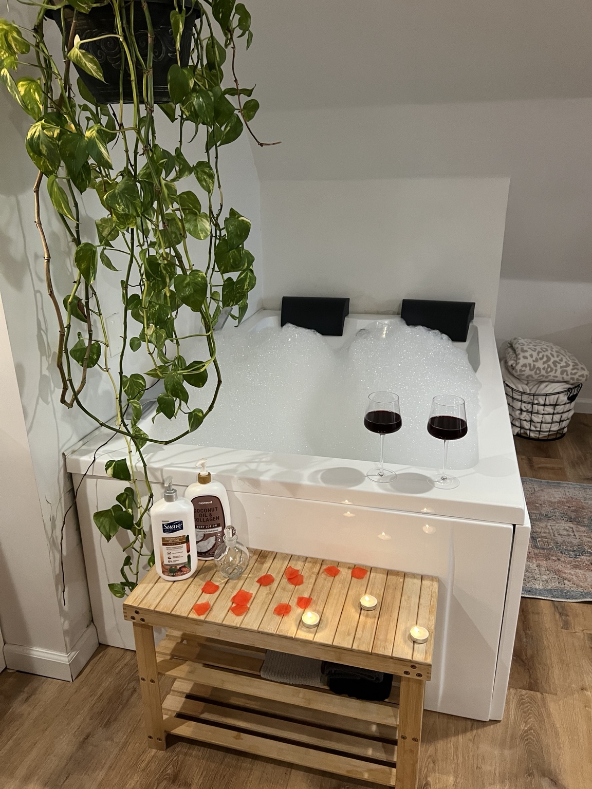 Two-person soaking tub filled with bubbles, wine glasses and candlelight